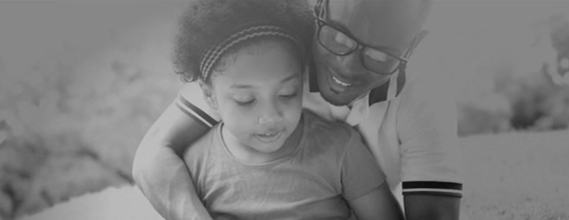 Black and white photo of a Black father and daughter hugging and smiling together