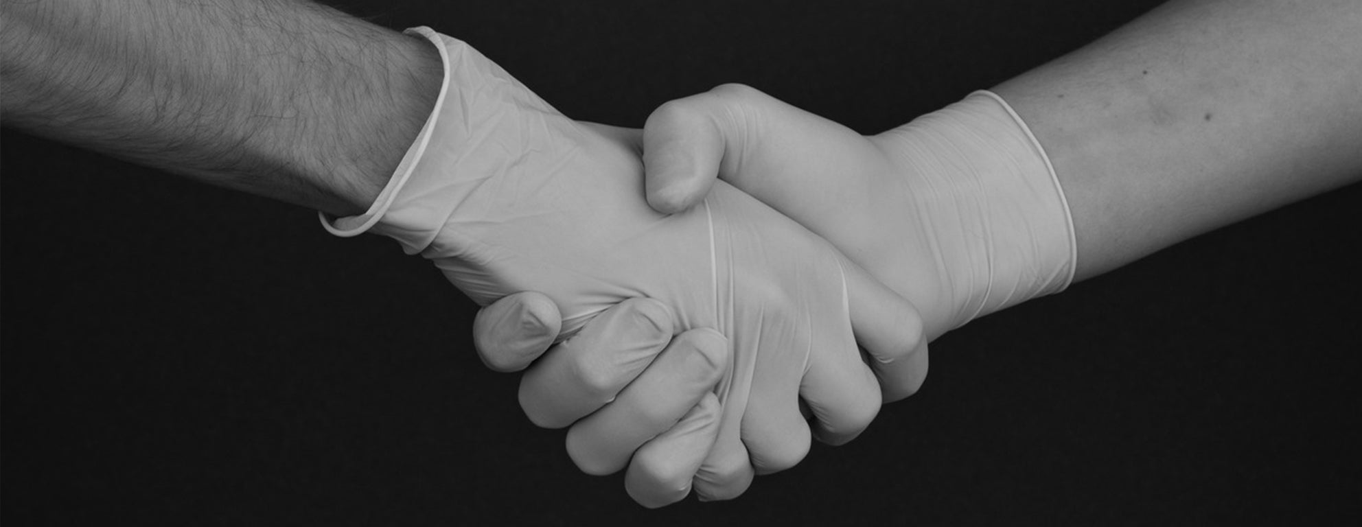Black and white close up of two hands with medical gloves shaking